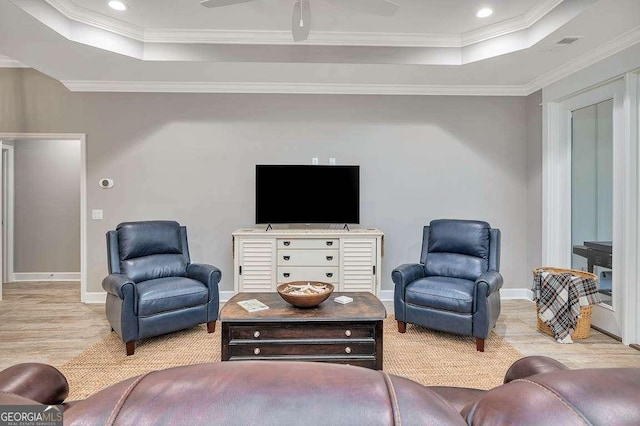 living room featuring ceiling fan, a raised ceiling, and ornamental molding