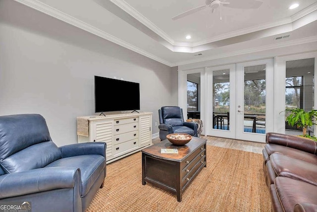 living room featuring a raised ceiling, ceiling fan, french doors, and ornamental molding