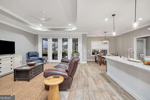 living room with french doors, light hardwood / wood-style flooring, a raised ceiling, and ornamental molding