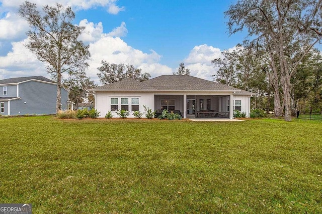 rear view of house with a yard and a sunroom