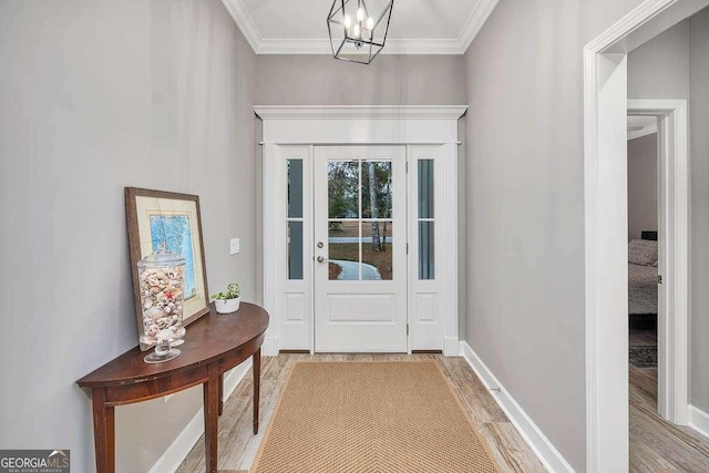 entryway with hardwood / wood-style floors, a notable chandelier, and ornamental molding