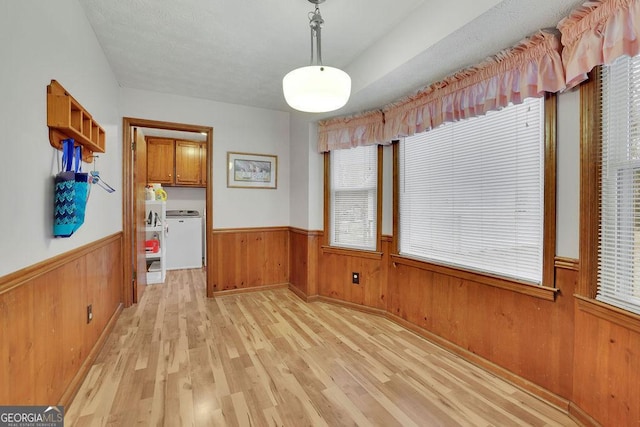 unfurnished dining area with wooden walls and light hardwood / wood-style flooring