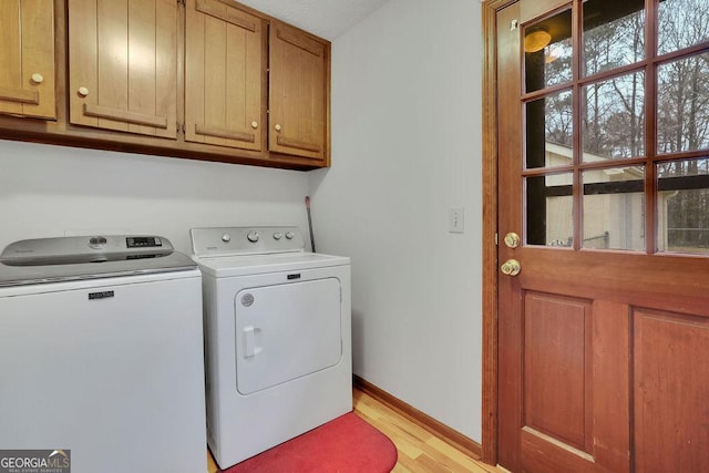 laundry room with light hardwood / wood-style floors, cabinets, and washing machine and dryer