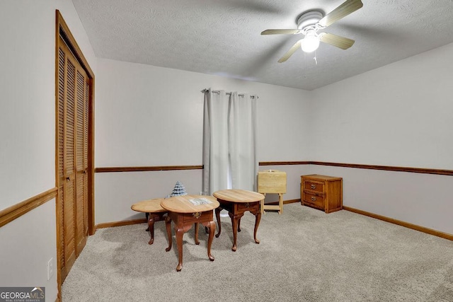 living area featuring a textured ceiling, ceiling fan, and light carpet