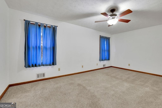 carpeted empty room with ceiling fan and a textured ceiling