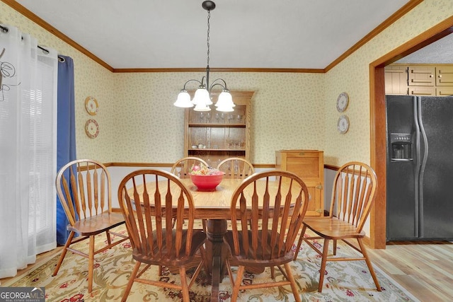 dining area with light hardwood / wood-style flooring, crown molding, and a notable chandelier