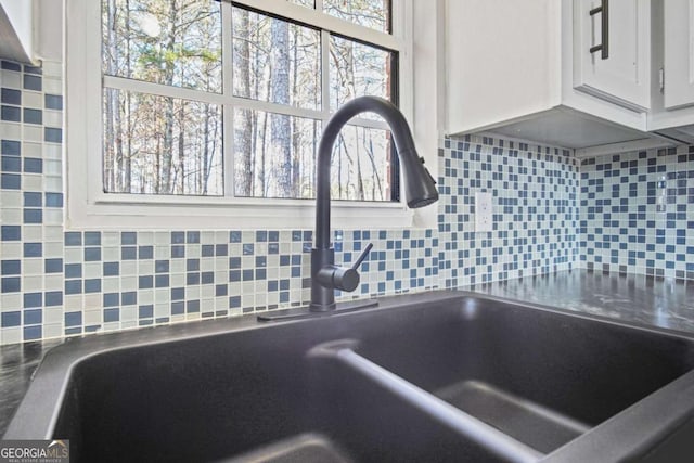 room details with sink, white cabinetry, and backsplash