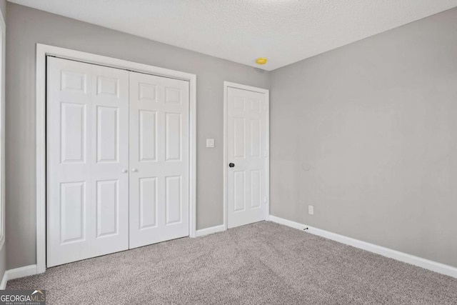 unfurnished bedroom featuring a closet, carpet floors, and a textured ceiling