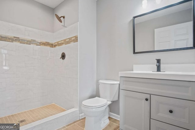 bathroom featuring tile patterned flooring, vanity, tiled shower, and toilet