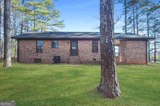 rear view of house with central AC and a yard