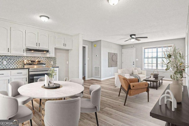 dining room with ceiling fan, light hardwood / wood-style floors, and a textured ceiling