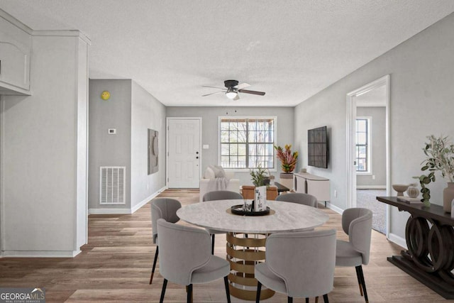 dining room featuring a textured ceiling, light hardwood / wood-style flooring, and ceiling fan