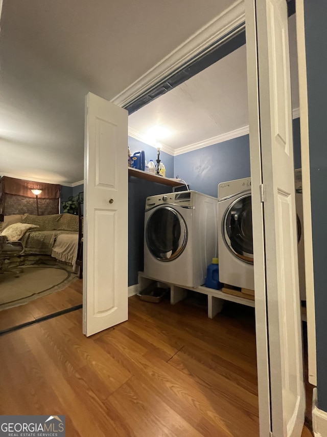 laundry area featuring hardwood / wood-style flooring, washer and dryer, and ornamental molding