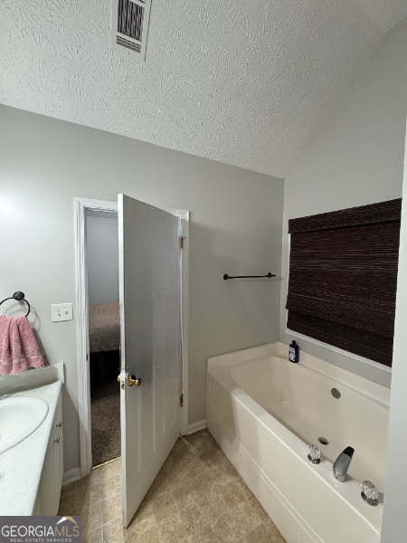 bathroom featuring a textured ceiling, vanity, and a tub to relax in