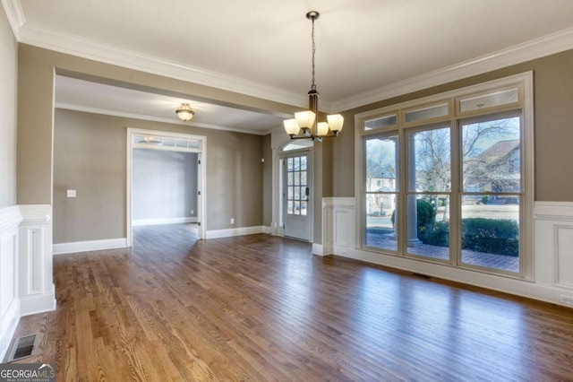 unfurnished dining area with hardwood / wood-style floors, ornamental molding, and an inviting chandelier