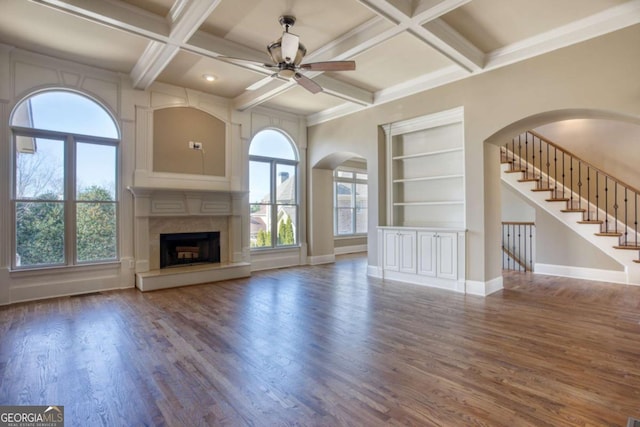 unfurnished living room with beam ceiling, built in shelves, ceiling fan, coffered ceiling, and a fireplace