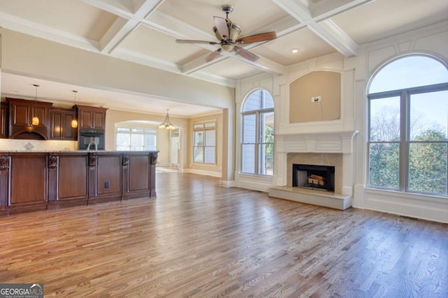 unfurnished living room with ceiling fan with notable chandelier, coffered ceiling, and hardwood / wood-style flooring