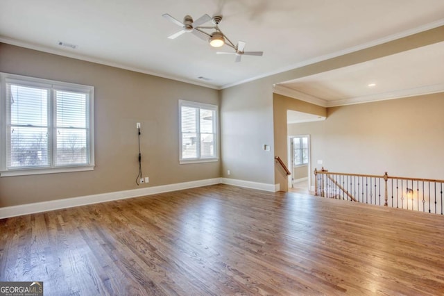 spare room with ceiling fan, wood-type flooring, a healthy amount of sunlight, and ornamental molding