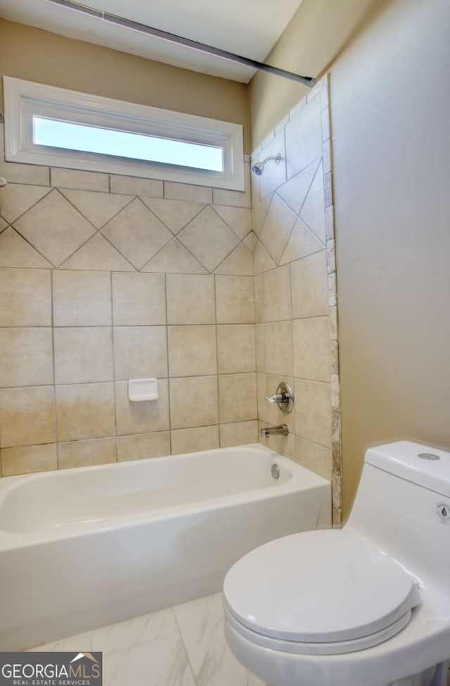 bathroom with tiled shower / bath combo and toilet