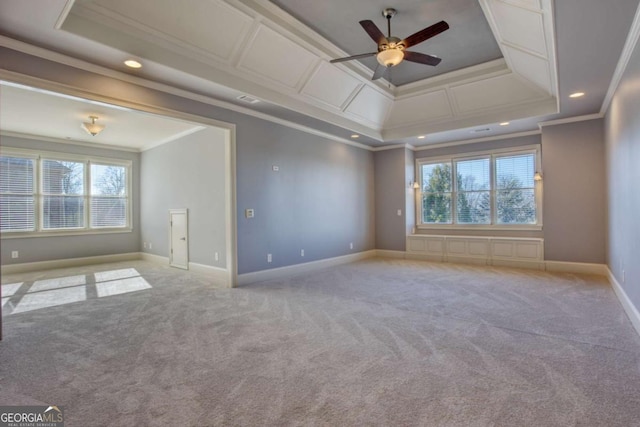 empty room featuring a raised ceiling, ceiling fan, light colored carpet, and ornamental molding