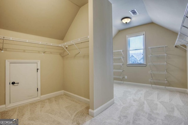 walk in closet featuring light colored carpet and lofted ceiling