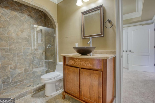 bathroom with vanity, toilet, tiled shower, and crown molding