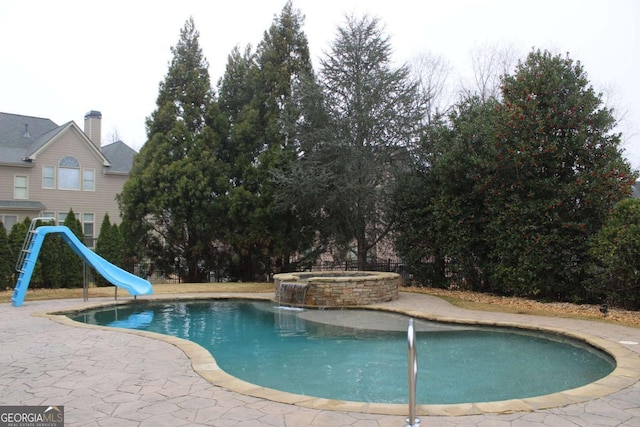 view of pool featuring an in ground hot tub and a water slide