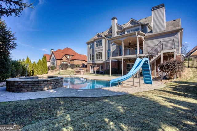 view of swimming pool featuring a yard, an outdoor hot tub, ceiling fan, and a water slide