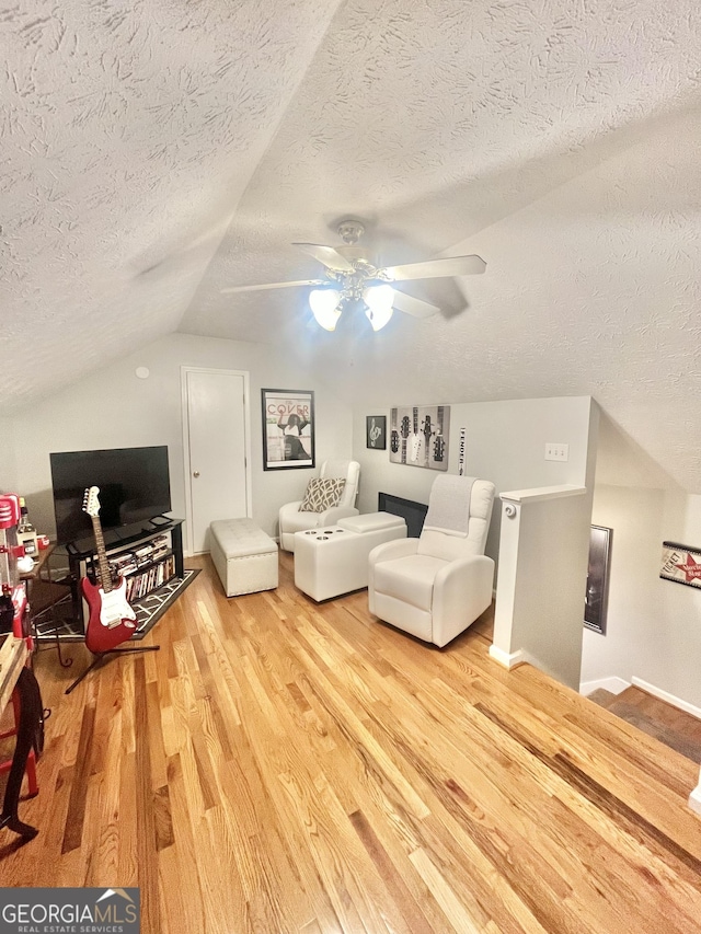 bedroom featuring ceiling fan, light hardwood / wood-style floors, a textured ceiling, and vaulted ceiling