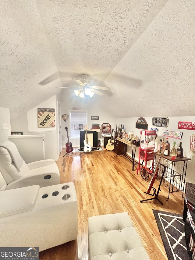 living room featuring a textured ceiling, ceiling fan, vaulted ceiling, and hardwood / wood-style flooring