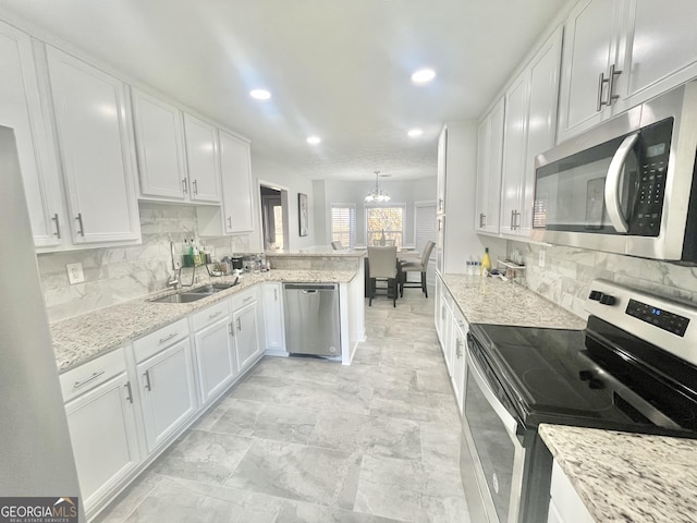 kitchen with decorative light fixtures, white cabinetry, kitchen peninsula, stainless steel appliances, and a chandelier