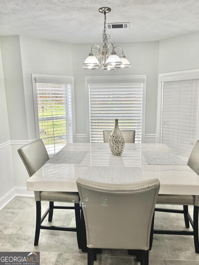 dining room featuring a textured ceiling and a chandelier