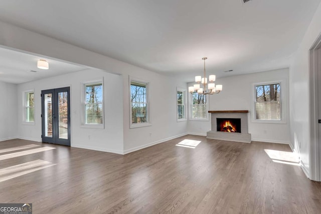 unfurnished living room featuring a chandelier, a fireplace, and wood-type flooring