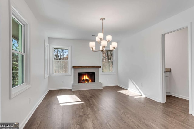 unfurnished living room featuring a fireplace, dark hardwood / wood-style floors, and a notable chandelier