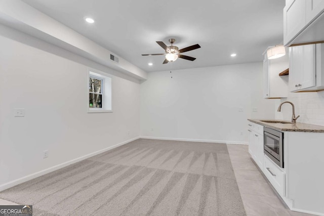 interior space featuring stainless steel microwave, sink, white cabinets, and dark stone counters