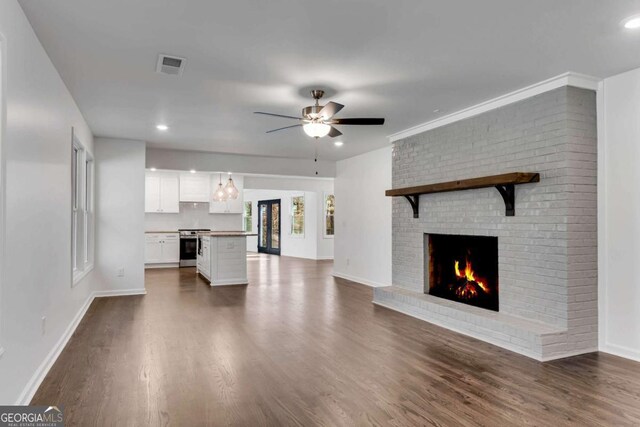 unfurnished living room featuring a fireplace, dark hardwood / wood-style floors, and ceiling fan