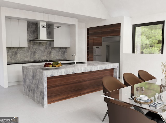 kitchen featuring a sink, backsplash, modern cabinets, and wall chimney range hood