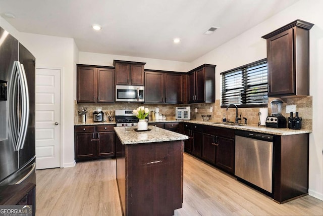 kitchen featuring a kitchen island, sink, appliances with stainless steel finishes, and light hardwood / wood-style flooring