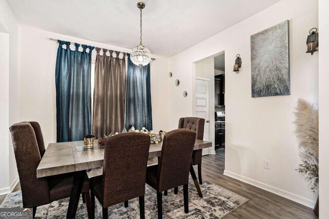 dining room with dark wood-type flooring and an inviting chandelier