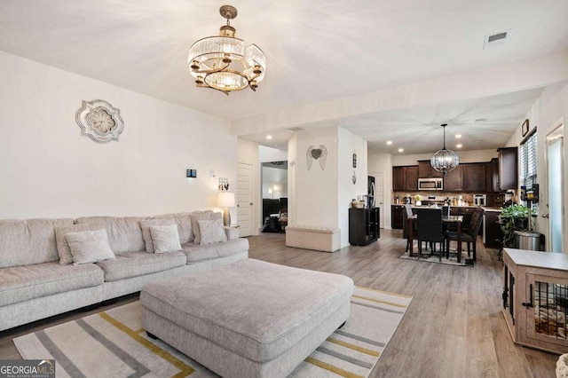 living room featuring light hardwood / wood-style flooring and a notable chandelier