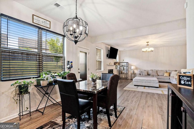 dining area with light hardwood / wood-style floors and a chandelier