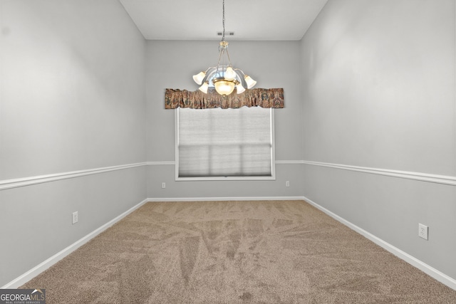 spare room featuring carpet flooring and a notable chandelier