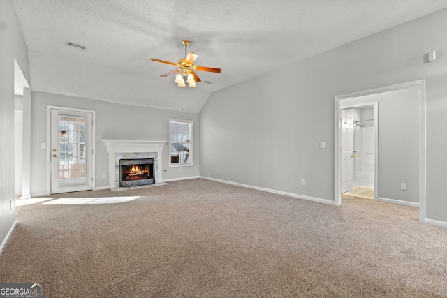 unfurnished living room featuring ceiling fan, lofted ceiling, carpet floors, and a high end fireplace