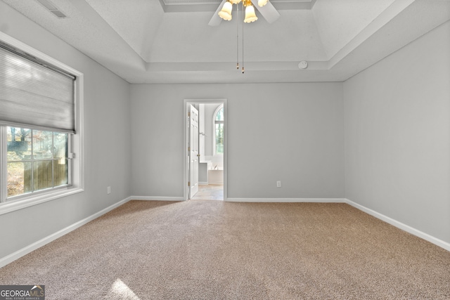 empty room featuring carpet, a raised ceiling, and ceiling fan