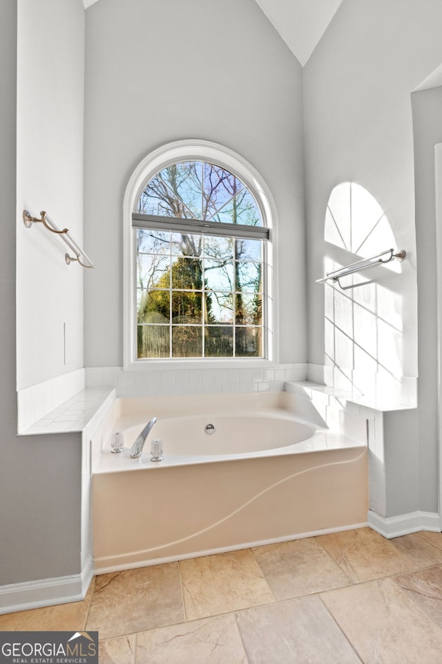 bathroom with lofted ceiling and a tub to relax in