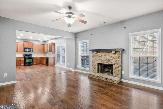 unfurnished living room featuring a fireplace, dark hardwood / wood-style floors, and ceiling fan