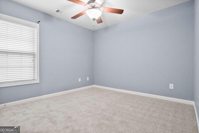 carpeted spare room featuring ceiling fan and a healthy amount of sunlight