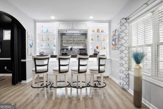 bar featuring built in shelves, white cabinetry, and light hardwood / wood-style floors