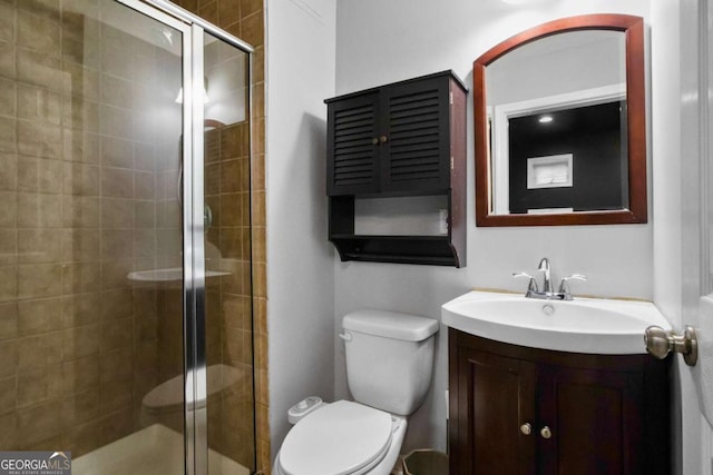 bathroom featuring vanity, toilet, and a shower with door