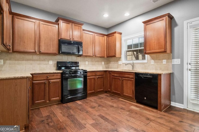 kitchen featuring backsplash, light stone counters, sink, black appliances, and dark hardwood / wood-style floors